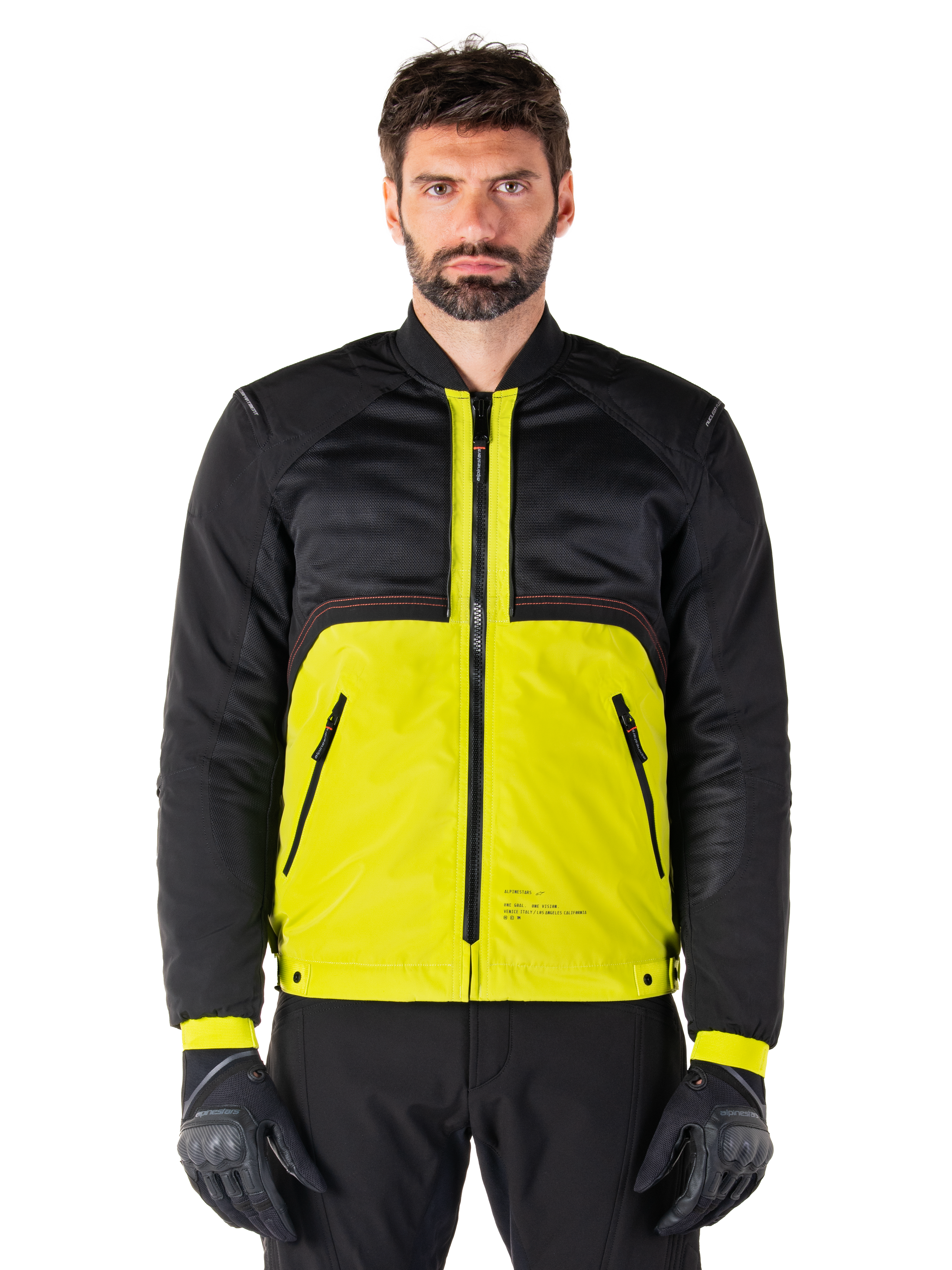 Alpinestars Mootant Waterproof Parka, modulær motorcykeljakke, Lime Punch og sort, båret af en mandlig model med sorte handsker og bukser, med en livlig gul underdel og sort overkrop og ærmer, utilitaristisk design til kørsel i alt slags vejr