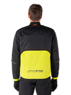 Alpinestars Mootant vandtæt parka, motorcykeljakke, Lime Punch og sort, set bagfra med sort mesh-overdel til ventilation og limefarvet underdel med MO.ST.EQ.-logo, vist med sorte bukser og handsker