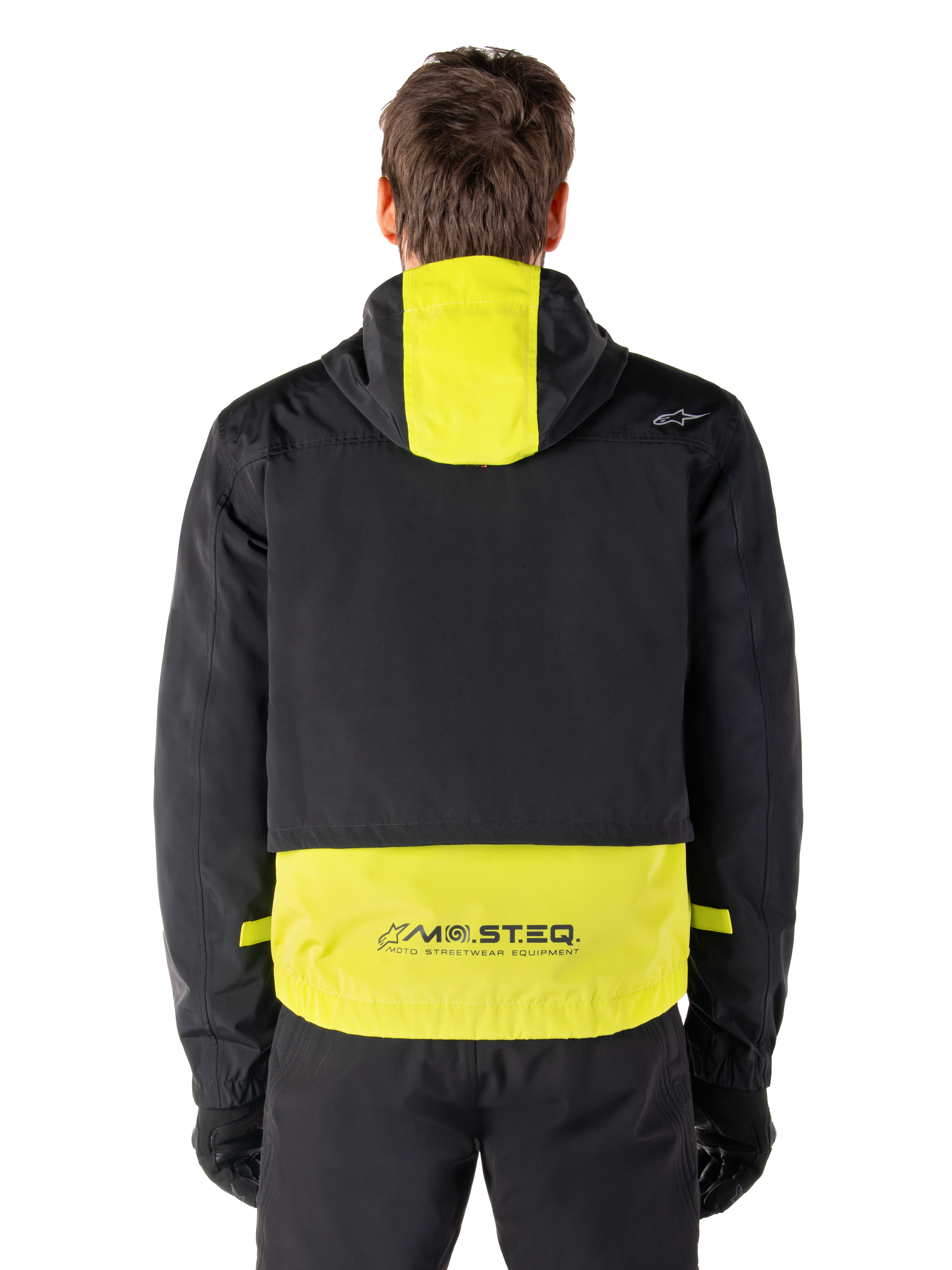 Alpinestars Mootant vandtæt parka, motorcykeljakke, Lime Punch og sort, set bagfra der viser designet med hætte og reflekterende MO.ST.EQ.-branding på den nederste del af ryggen, båret med sorte kørebukser og handsker.