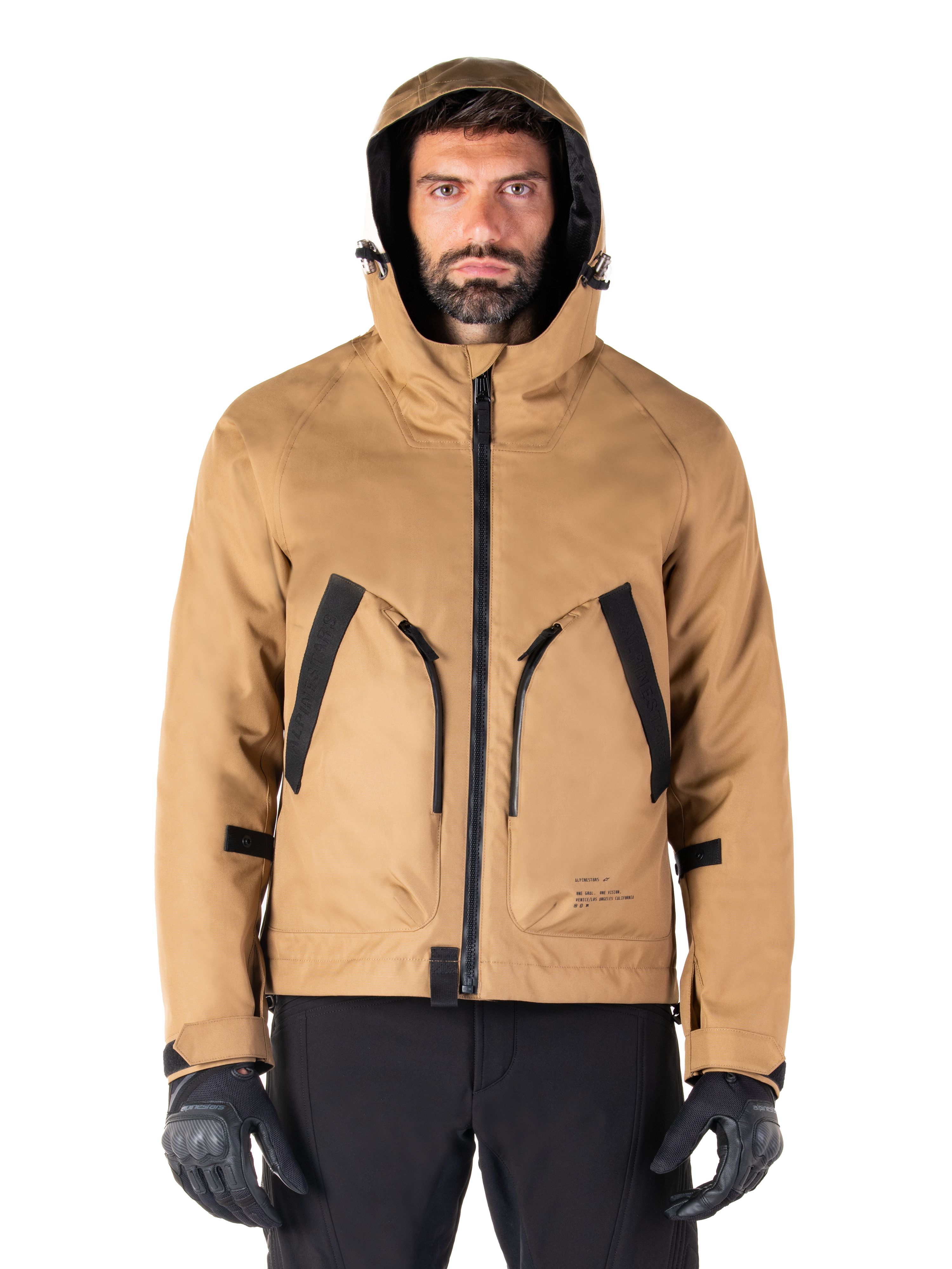 Alpinestars Morush vandtæt parka, motorcykeljakke, Utility Brown, hætteklædt streetwear-inspireret design med store frontlommer med sorte detaljer, båret med sorte kørehandsker og bukser, moderne urbant motorcykeludstyr