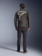 Alpinestars Axton jakke, motorcykeljakke, Black Anthracite Red Tangerine, set bagfra med stort gråt Alpinestars-logo og stjernegrafik, harmonikapaneler på skuldrene, båret med sorte bukser og afslappede sorte sko.