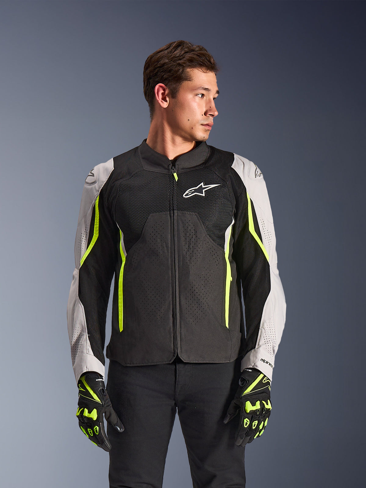 Alpinestars AST V3 Air jakke, tekstil motorcykeljakke, sort og sølv med neongule detaljer, med store mesh-ventilationspaneler og laserperforeringer, båret af en model med matchende handsker, sport-performance køreudstyr