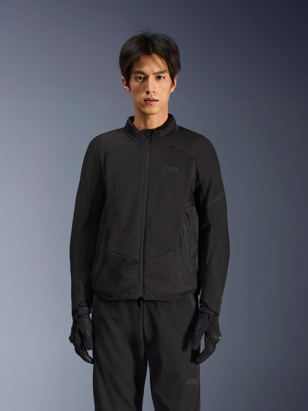 Alpinestars Aeroshell Airflow-jakke i Black Anthracite, letvægts motorcykeljakke med laserperforeret ventilation på brystet og ærmerne, åndbare mesh-paneler og et stilrent sport-cut design, båret af en model med sorte kørehandsker