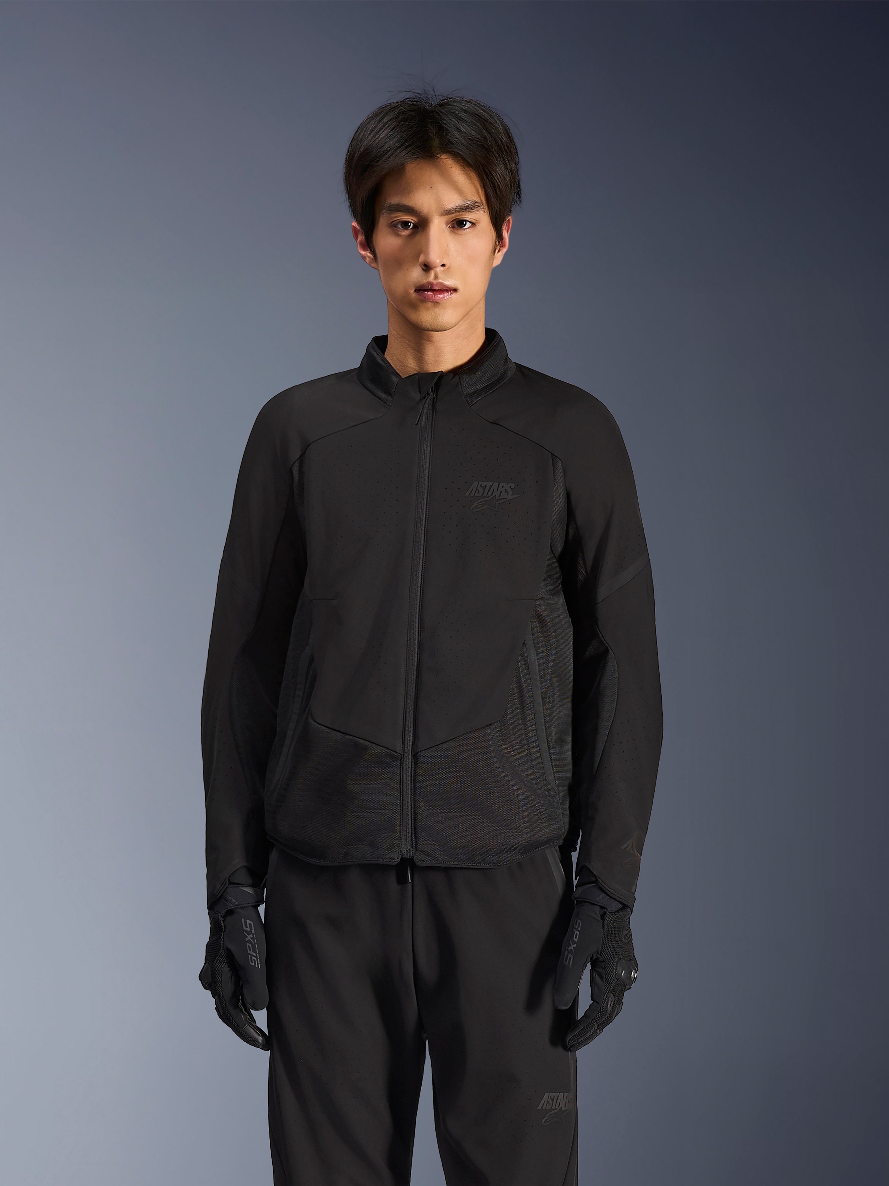 Alpinestars Aeroshell Airflow-jakke i Black Anthracite, letvægts motorcykeljakke med laserperforeret ventilation på brystet og ærmerne, åndbare mesh-paneler og et stilrent sport-cut design, båret af en model med sorte kørehandsker