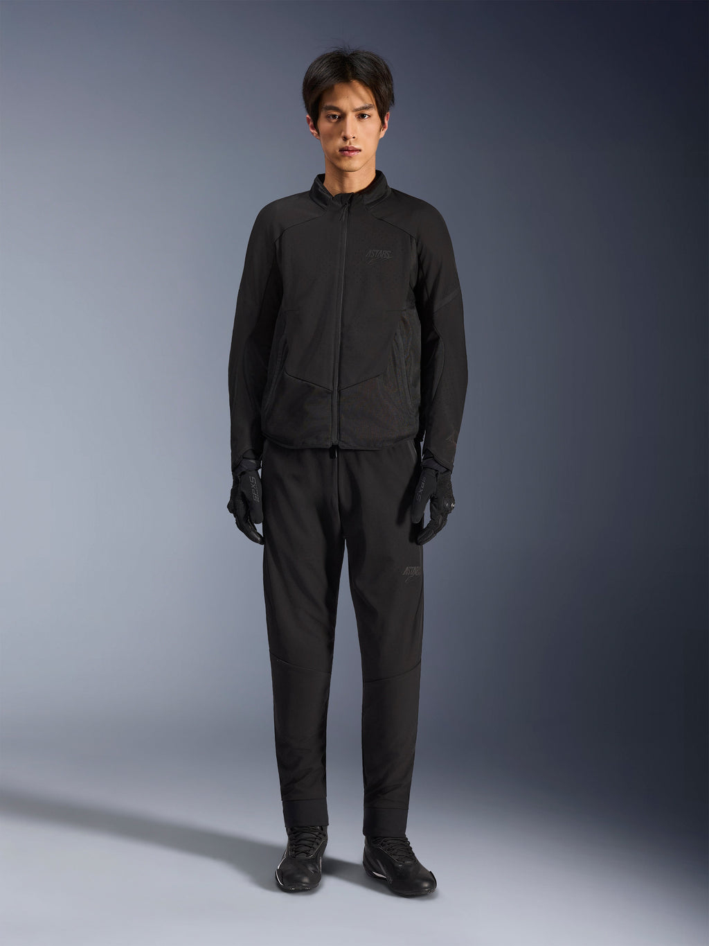 Alpinestars Aeroshell Airflow Jakke, sort motorcykeljakke, båret af model med matchende sorte bukser og handsker, med laserperforerede bryst- og sidemesh-paneler, sport-cut pasform til ydeevne i varmt vejr