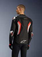 Alpinestars T-GP Air-jakke i Black Red Fluo, set bagfra i trekvart-profil på en model, der fremhæver den aerodynamiske pukkel, Racing GP DFS ekstern beskyttelse på skuldre og albuer, laserperforerede mesh-paneler, hvide og røde fluo-detaljer, sport-cut motorcykeljakke i tekstil.