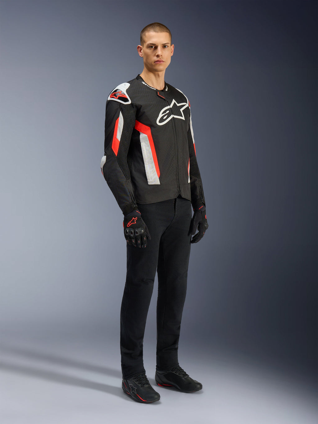 Alpinestars T-GP Air jakke, Black Red Fluo, båret af model med sorte kørebukser og handsker, med laserperforerede tekstilpaneler, hvidt Alpinestars-branding og røde accenter, sport-motorcykeljakke til landevejskørsel i varmt vejr