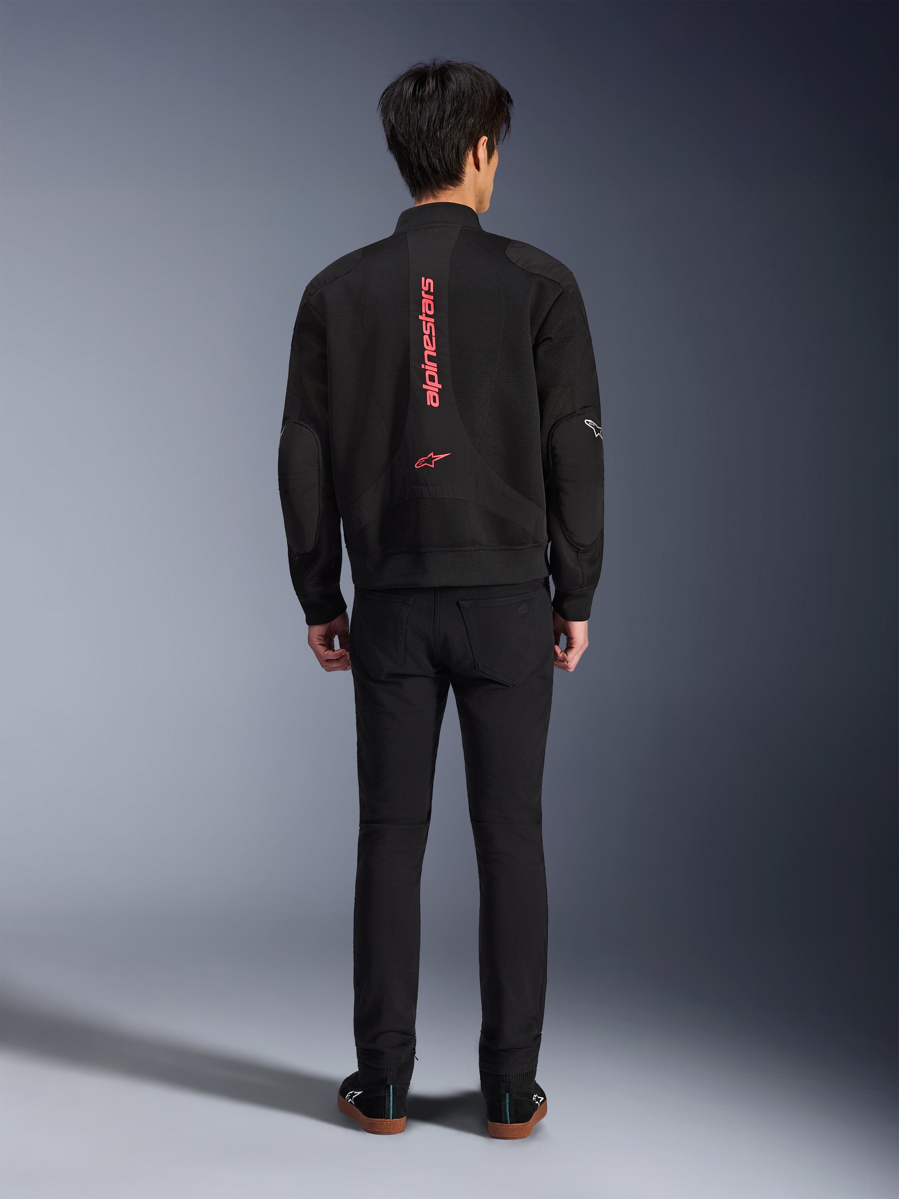 Alpinestars Flight Air-jakke i sort og klar rød, urban motorcykeljakke i bomber-stil set bagfra, med lodret rød Alpinestars-branding og logo på ryggen, letvægts 3D-mesh-konstruktion, båret med sorte bukser for et moderne look.