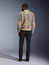 Alpinestars Flight Air-jakke, tan urban motorcykeljakke, set bagfra, viser åndbare 3D-mesh-paneler og lodret logo, båret med sorte bukser for et moderne streetstyle-look