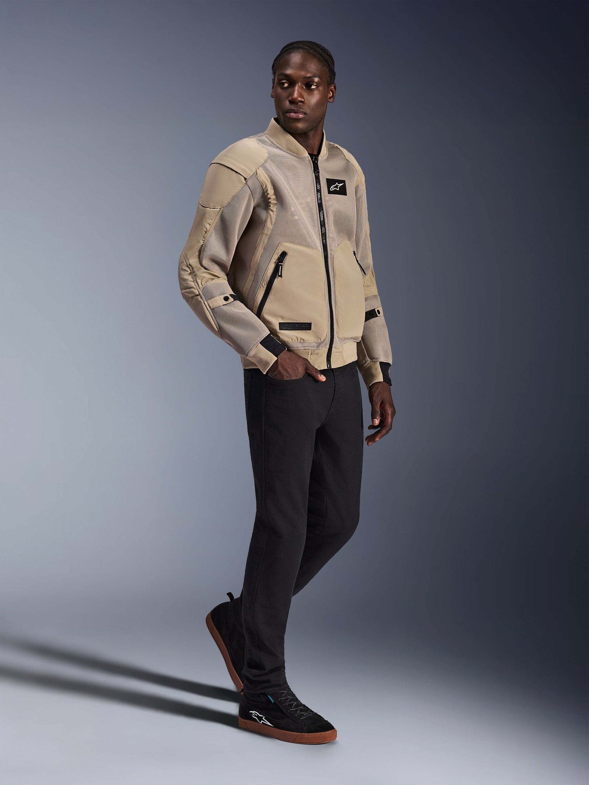 Alpinestars Flight Air-jakke, urban motorcykeljakke, farven Aluminum, bæres af model med sorte bukser og sorte sneakers, med 3D-mesh ventilationspaneler og et design i bomber-stil, moderne street-stil til bykørsel.
