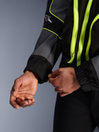Alpinestars Unite jakke, urban motorcykeljakke, sort og asfalt med neongule detaljer, nærbillede af hænder, der justerer den elastiske ærmemanchet, minimalistisk streetwear-inspireret beskyttelsesudstyr