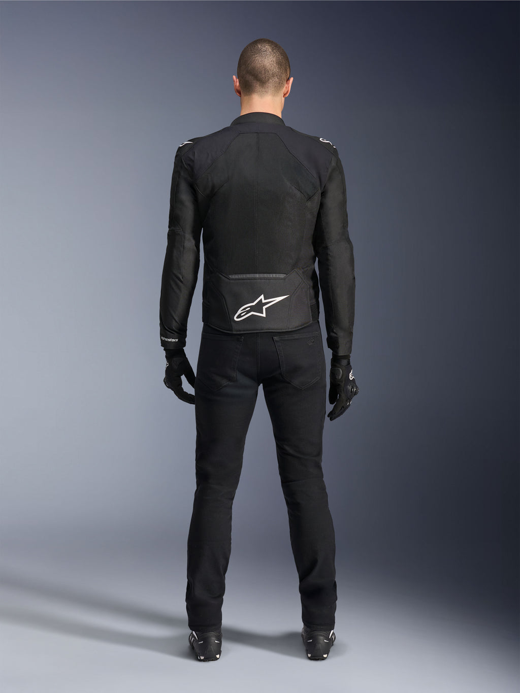 Alpinestars Viper Air V4 Jacket, Black Textile Motorcycle Jacket, back view with white Alpinestars star logo on lower back, worn with black riding pants and gloves, summer gear for road and sport riding