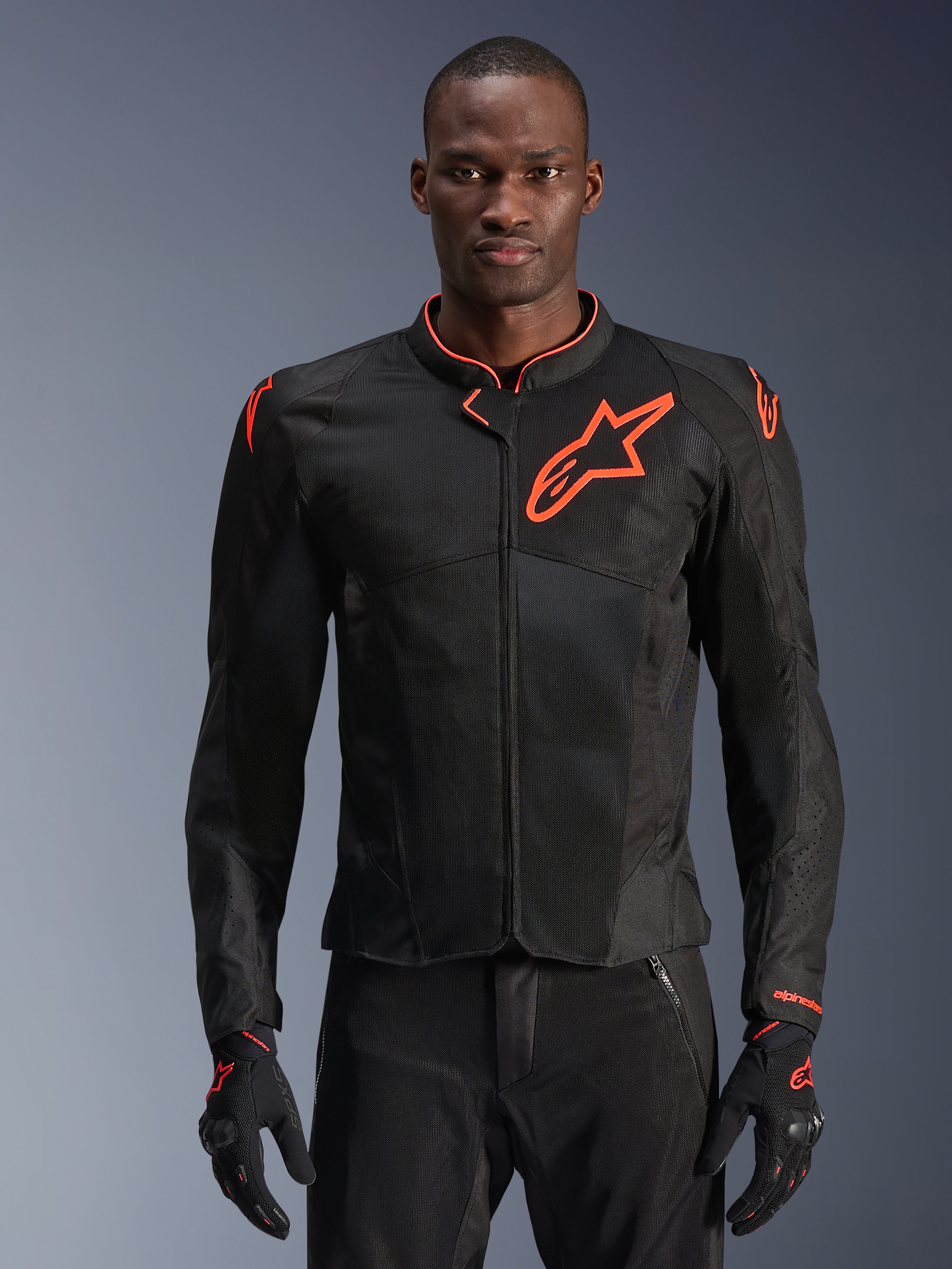 Alpinestars Viper Air V4 Jacket, Black and Red Fluo motorcycle jacket, ventilated mesh construction with prominent red star logo, worn by model with matching gloves, sport performance design