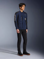 Alpinestars Dice Jakke, mørkeblå og sort, moderne motorcykeljakke i felt-stil båret af en model med sorte bukser og sorte high-top sneakers, med flere praktiske lommer, lodret Alpinestars-branding på ærmet og vævede mærker, urbant moderne køreudstyr
