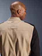 Alpinestars Dice Jacket, urban motorcykeljakke, tan og sort, tætbillede af krave og skulder på ryggen, broderet logo, robust polybomulds-twill-konstruktion, gadeklar arbejdstøjsstil.
