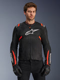 Alpinestars T-Sps Air V2 Jacket, Black and Red Fluo motorcycle jacket, large white Astars logo on chest, textured tech mesh construction for airflow, worn by model with black riding gloves, sports cut design with red accents on shoulders and sleeves