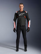 Mandlig model iført Alpinestars T-Sps Air V2 jakke i sort, hvid og rød fluo, med store tech-mesh-paneler og tydelig hvid branding på brystet og ærmerne, kombineret med sorte tekniske kørebukser og handsker, urban sport motorcykeludstyr