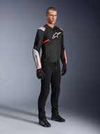 Alpinestars T-Sps Air V2 jakke, sort, hvid og rød fluo, båret af en mandlig model med sorte køre-bukser og handsker, tekstil motorcykeljakke med store mesh-paneler, hvide skulder- og underarmssektioner og et markant Alpinestars-logo på brystet