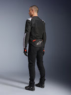 Alpinestars T-Sps Air V2-jakke, tekstilmotorcykeljakke, sort, hvid og rød fluo, set bagfra på model, mesh-paneler til ventilation, hvidt Astars-logo på den nedre del af ryggen, stylet med sorte kørebukser og handsker