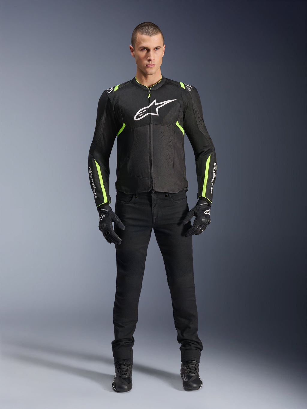 Alpinestars T-Sps Air V2 Jakke, Sort og Gul Fluo, tekstil motorcykeljakke med mesh-paneler, båret af mandlig model med sorte bukser og handsker, med hvidt Alpinestars-logo på brystet, urban sport-køreudstyr
