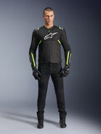 Alpinestars T-Sps Air V2 Jakke, Sort og Gul Fluo, tekstil motorcykeljakke med mesh-paneler, båret af mandlig model med sorte bukser og handsker, med hvidt Alpinestars-logo på brystet, urban sport-køreudstyr