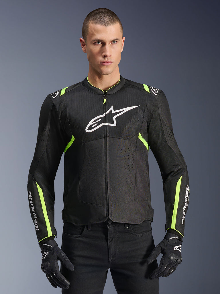 Alpinestars T-Sps Air V2-jakke i Black Yellow Fluo, mandlig model iført den ventilerede tekstiljakke med mesh-paneler og hvidt logo på brystet, kombineret med sorte kørehandsker, urbant motorcykeludstyr