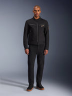 Alpinestars Bruiser jakke, sort urban motorcykeljakke, båret af model med sorte bukser og high-top sneakers, set forfra med brystlommer med lynlås og broderet logo, klassisk arbejdstøjsinspireret design til daglig pendling