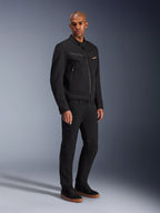 Alpinestars Bruiser-jakke, urban motorcykeljakke, sort, båret af en model med sorte bukser og sneakers, brystlommer med lynlås, polycotton twill-stof, stilrent arbejdstøjsinspireret design til bykørsel