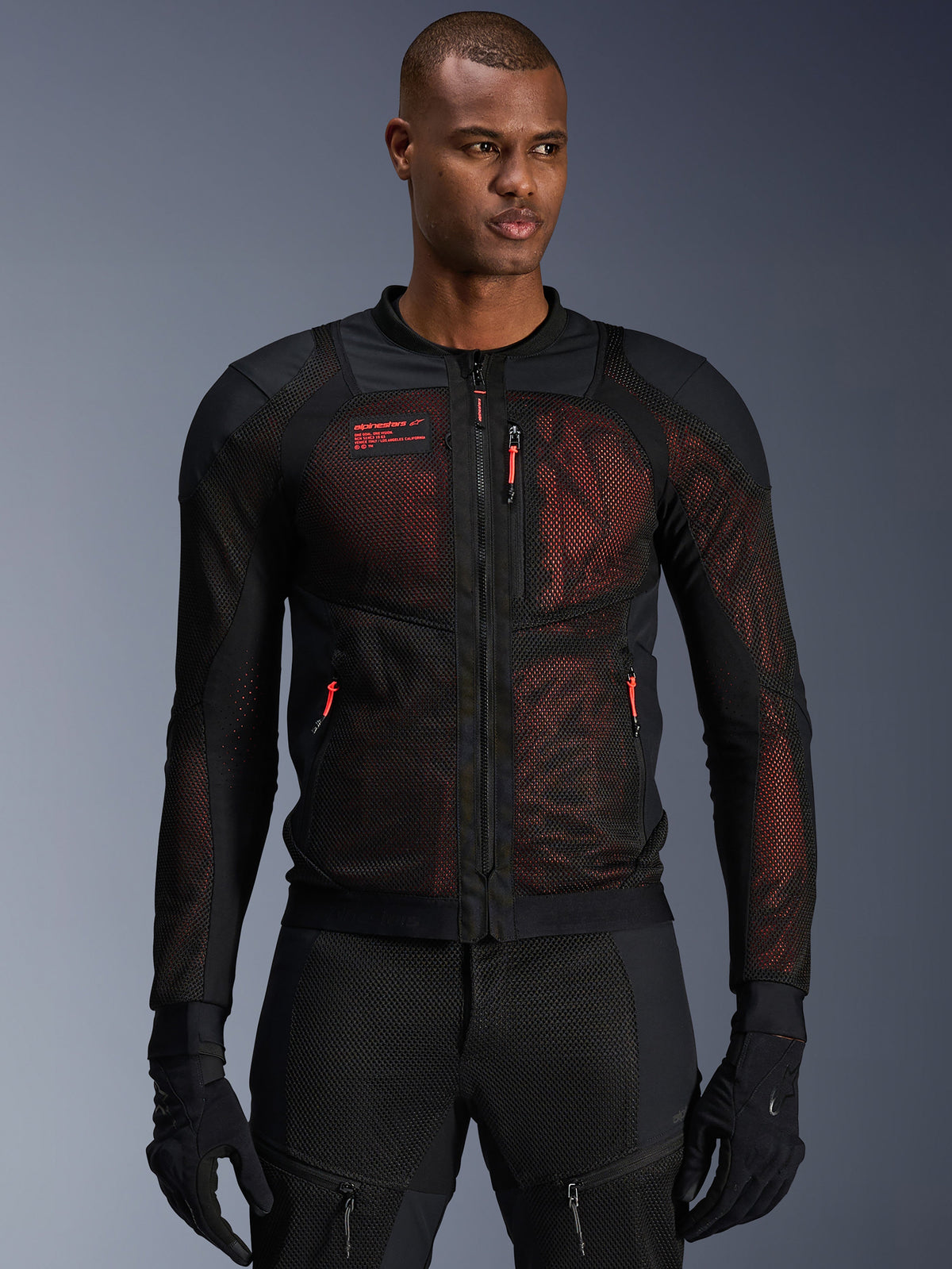 Alpinestars Troop-Air Pro Jakke, teknisk pansret motorcykeljakke i mesh, sort og rød fluo, bæres af en model, med store ventilationspaneler i mesh, rødt underlag og røde lynlåsstropper, urban kørestil