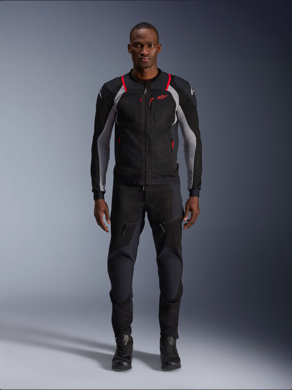 Alpinestars Troop-Air Pro Jakke, teknisk motorcykeljakke, sort, aske-grå og klar rød, med mesh-paneler og røde detaljer, båret af en mandlig model med sorte kørebukser og støvler, stilrent urbant design med teknisk ventilation.