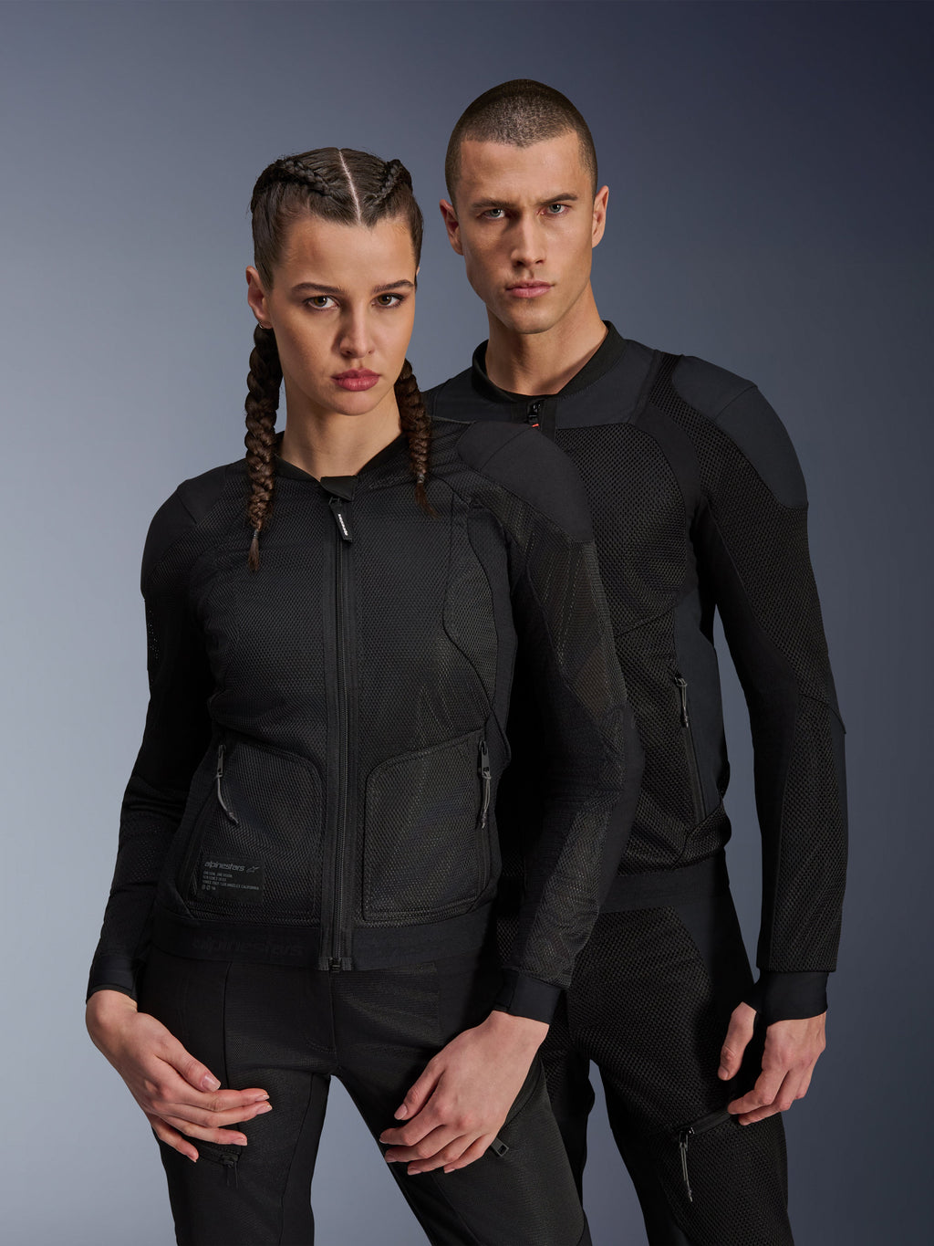 Alpinestars Troop-Air Pro Jakke, sorte tekniske pansrede luftjakker båret af mandlige og kvindelige modeller, med åndbare mesh-paneler og integreret beskyttelse, urbant motorcykeludstyr designet til kørsel i varmt vejr.