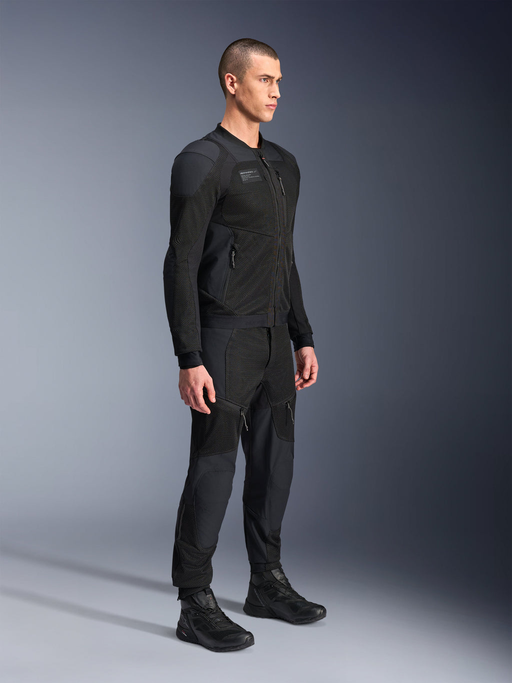 Alpinestars Troop-Air Pro jakke, teknisk pansret luftjakke, sort, båret af model med matchende sorte motorcykelbukser og støvler, med avanceret 2D tech mesh-struktur og åndbare ventilationspaneler, urban moderne køreudstyr.