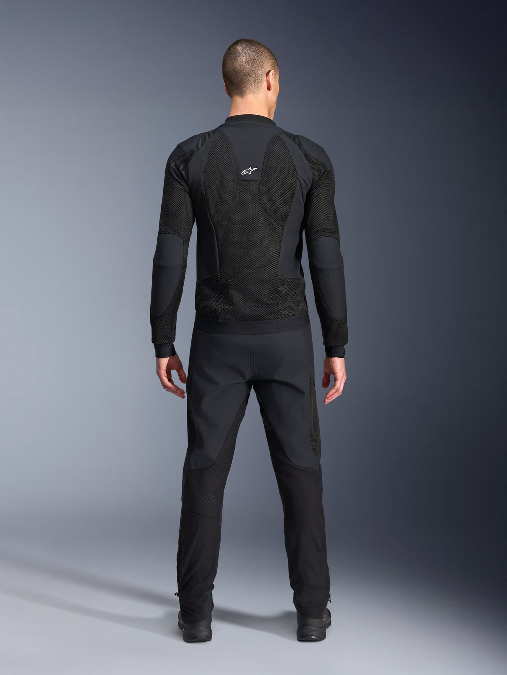 Alpinestars Troop-Air Pro jakke, set bagfra, sort, teknisk motorcykel-luftjakke med store mesh-ventilationspaneler og hvidt Alpinestars-logo, kombineret med sorte bukser, moderne urbant køreudstyr