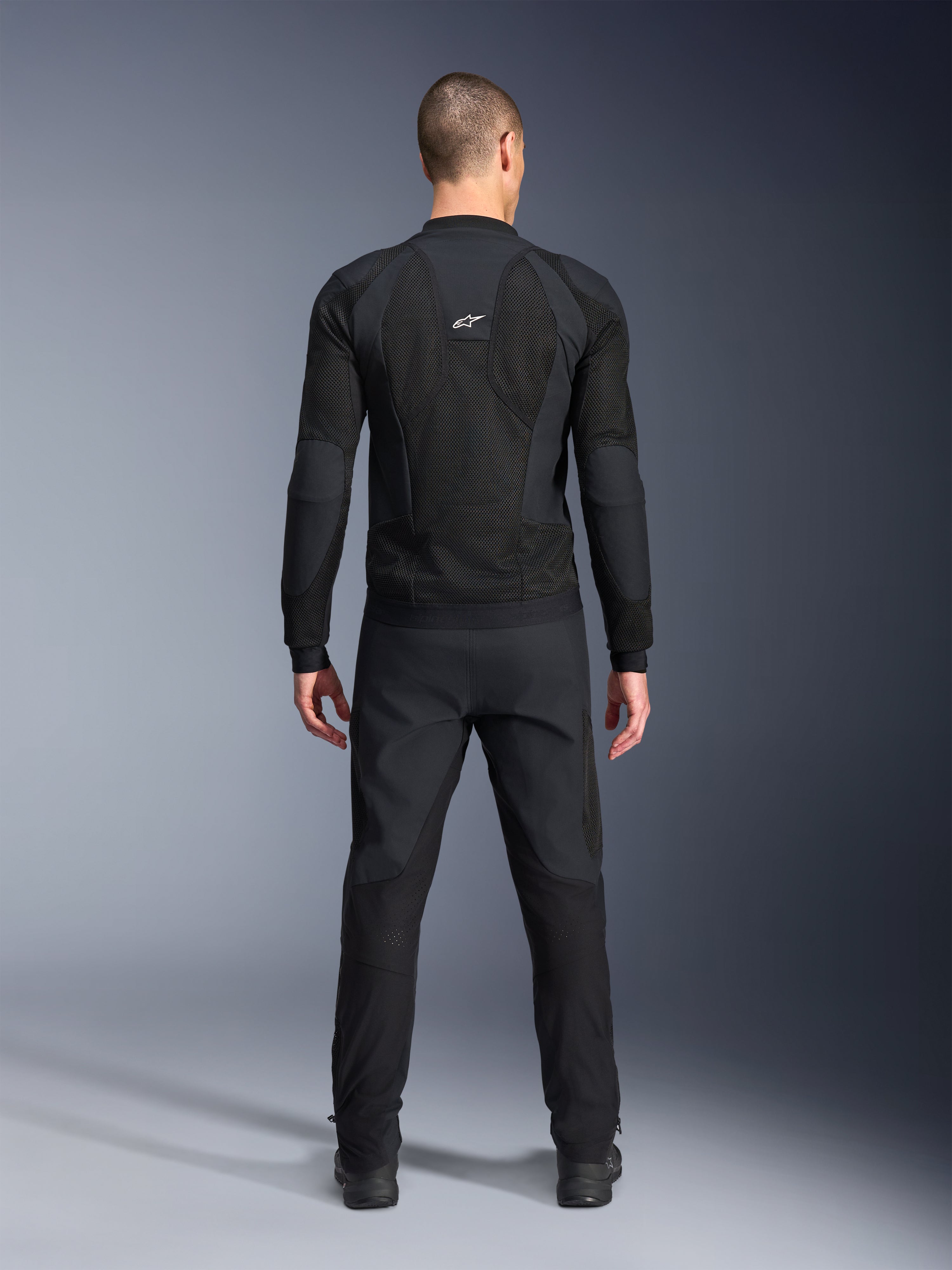 Alpinestars Troop-Air Pro jakke, set bagfra, sort, teknisk motorcykel-luftjakke med store mesh-ventilationspaneler og hvidt Alpinestars-logo, kombineret med sorte bukser, moderne urbant køreudstyr