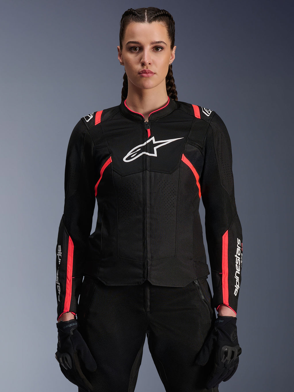 Alpinestars Stella T-SPS Air v2 jakke til kvinder, sort og Diva Pink, tekstil-motorcykeljakke med åndbare mesh-paneler og lyserøde detaljer, hvidt Alpinestars-logo på brystet, båret af en kvindelig model med sorte kørebukser og handsker