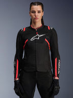 Alpinestars Stella T-SPS Air v2 jakke til kvinder, sort og Diva Pink, tekstil-motorcykeljakke med åndbare mesh-paneler og lyserøde detaljer, hvidt Alpinestars-logo på brystet, båret af en kvindelig model med sorte kørebukser og handsker
