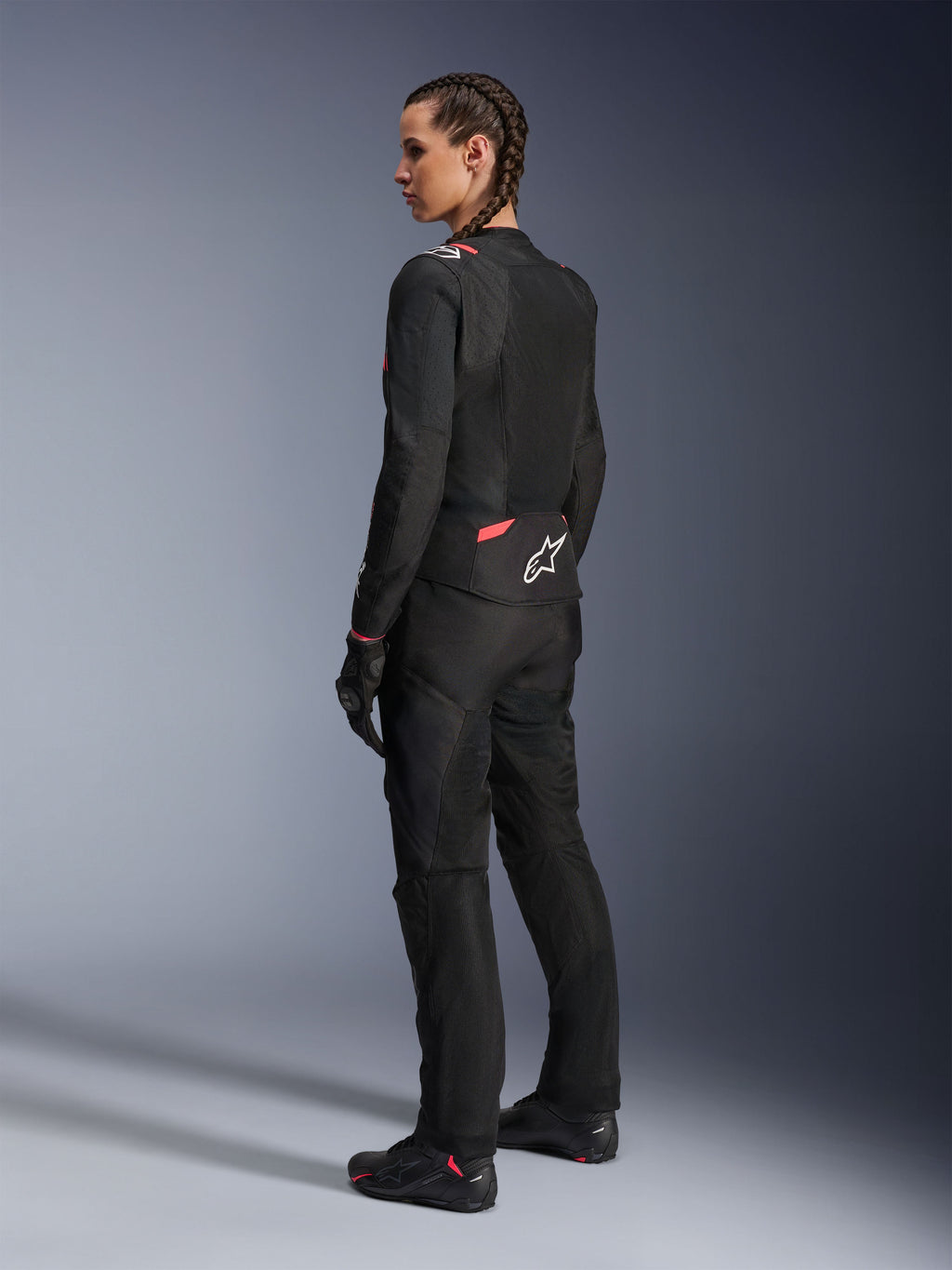 Alpinestars Stella T-Sps Air v2 jakke til damer, sort og Diva Pink, tekstil motorcykeljakke vist fra siden bagfra, store mesh-paneler for ventilation, hvidt stjernelogo på ryggen, båret med matchende sorte kørebukser, handsker og støvler