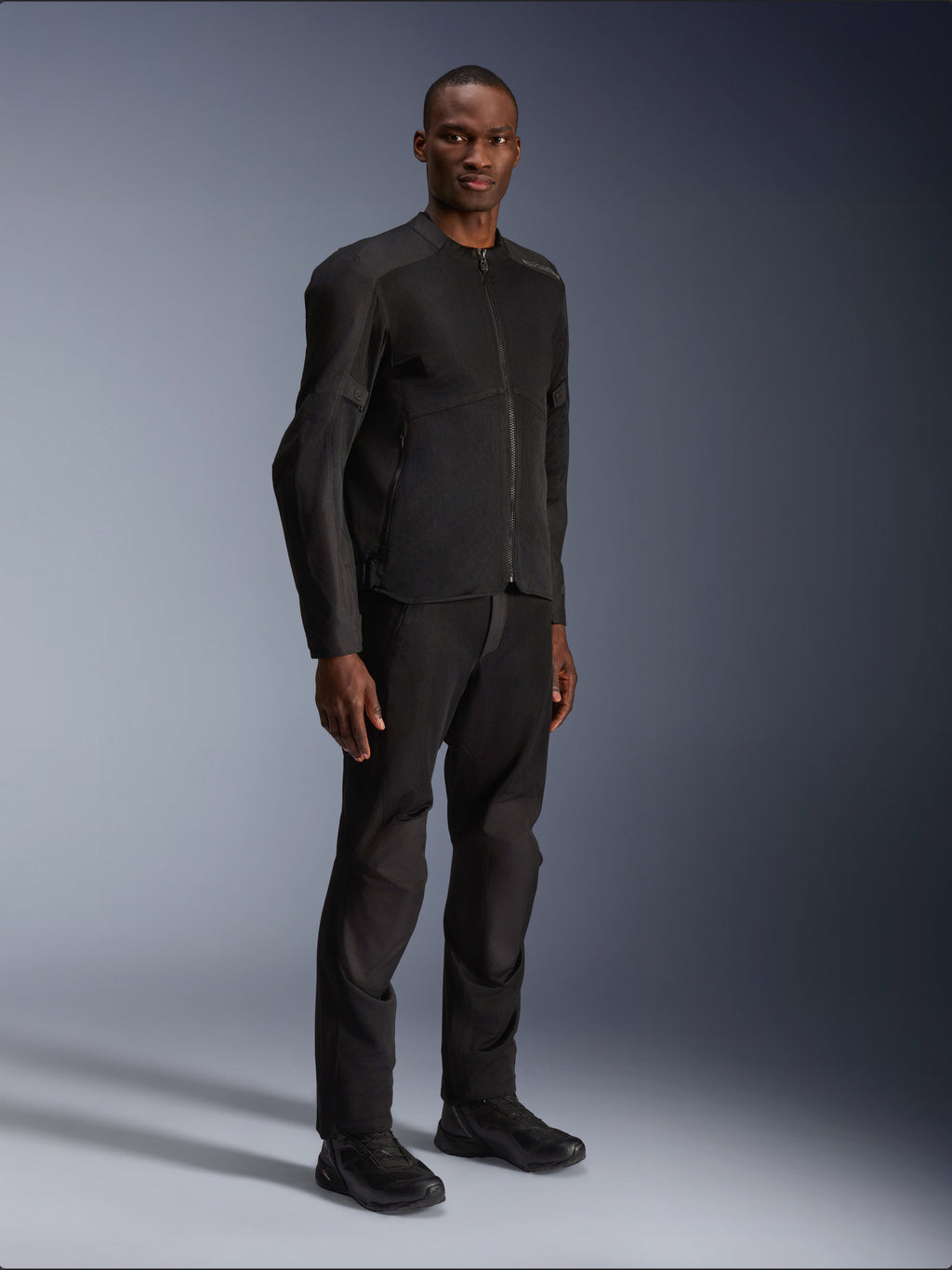 Alpinestars C-1 Air-jakke, sort, båret af en model med matchende sorte motorcykelbukser og sko, store tech mesh-paneler for luftgennemstrømning, ren urban æstetik med en strømlinet pasform