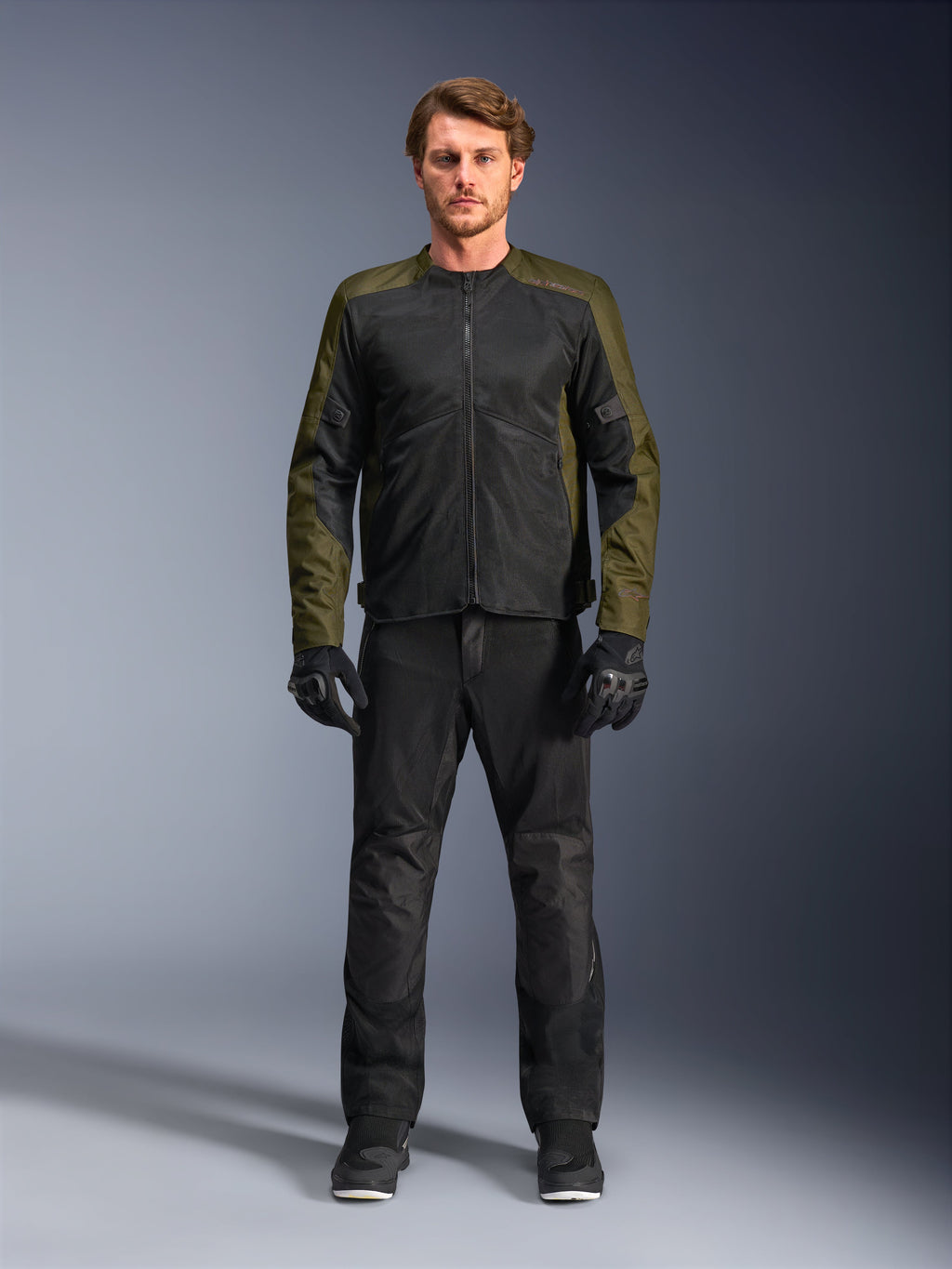 Alpinestars C-1 Air-jakke, khaki og sort, båret af mandlig model med sorte motorcykelbukser og handsker, letvægts tekstildesign med tech mesh-paneler, moderne urbant køreudstyr