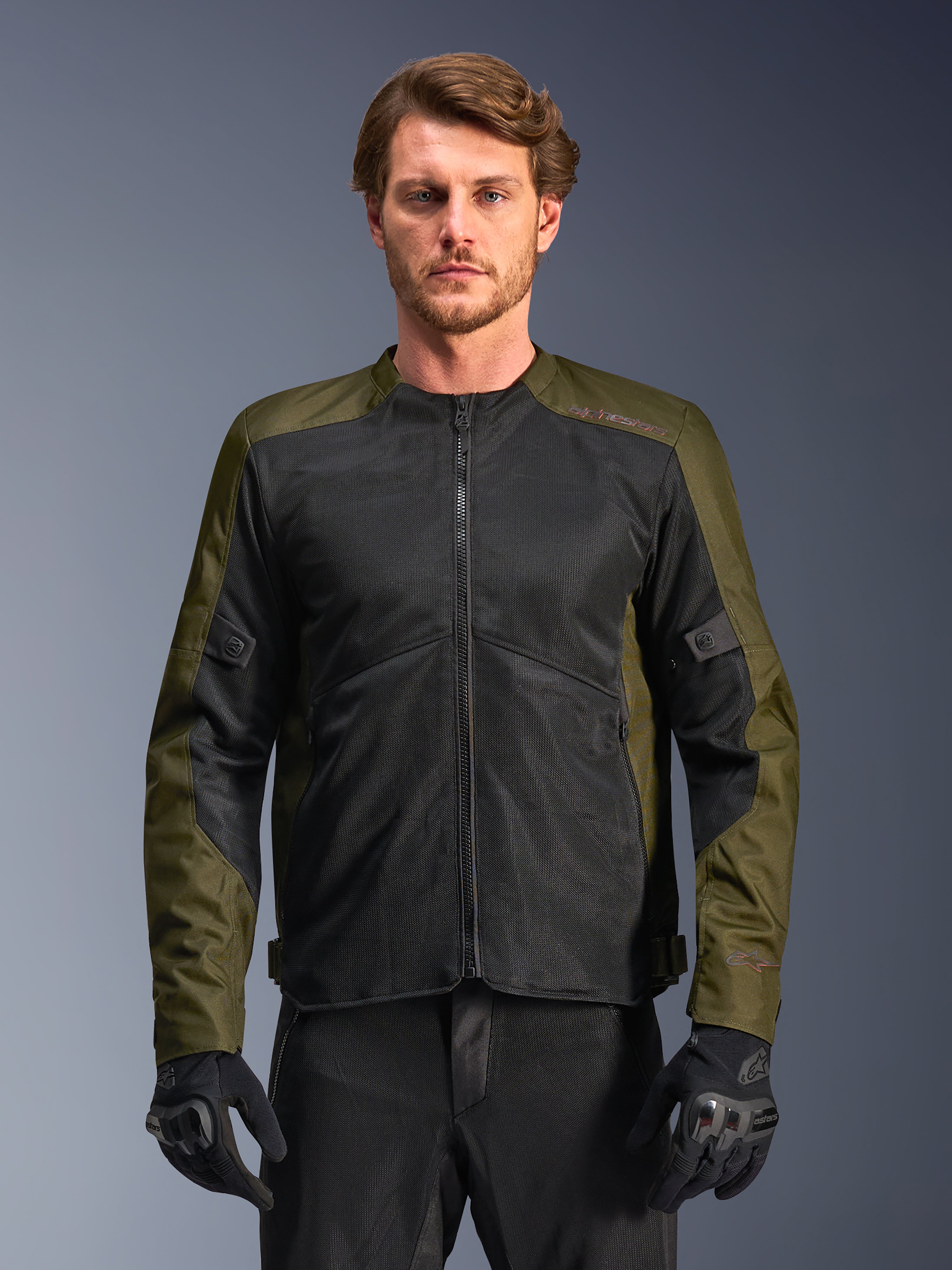 Alpinestars C-1 Air-jakke, khaki og sort, motorcykeljakke til mænd med store tech mesh-paneler for maksimal luftgennemstrømning, båret af en model med sorte motorcykelbukser og handsker, urbant moderne design til pendling.