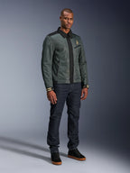 Alpinestars Ignite Air-jakke, Urban Gray Black Blue, urban motorcykeljakke, båret af en model med mørke denimjeans og sorte sneakers, med mesh-krop, traditionel skjortekrave, Harrington-inspireret silhuet og guldfarvet Alpinestars-branding.