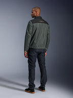 Alpinestars Ignite Air Jakke i Urban Gray Black Blue, set bagfra på model, med mesh-krop, sort skulderstykke og hvid tekst, stribede manchetter, kombineret med mørke denimjeans og sorte sneakers, urban livsstils-motorcykelbeklædning