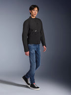 Alpinestars Provoke-jakke, urban motorcykeljakke, sort, båret af en mandlig model med blå jeans og sorte sneakers, teknisk tekstildesign med et lille Alpinestars-logo, fuldkrops livsstilsbillede til moderne bykørsel