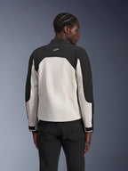 Alpinestars Provoke-jakke, urban motorcykeljakke, Black Metal Gray, set bagfra på en model, tofarvet tekstildesign med sorte skuldre og lysegråt rygpanel, Alpinestars-stjernelogo på kraven bagpå, kombineret med sorte bukser mod en blå gradueret baggrund