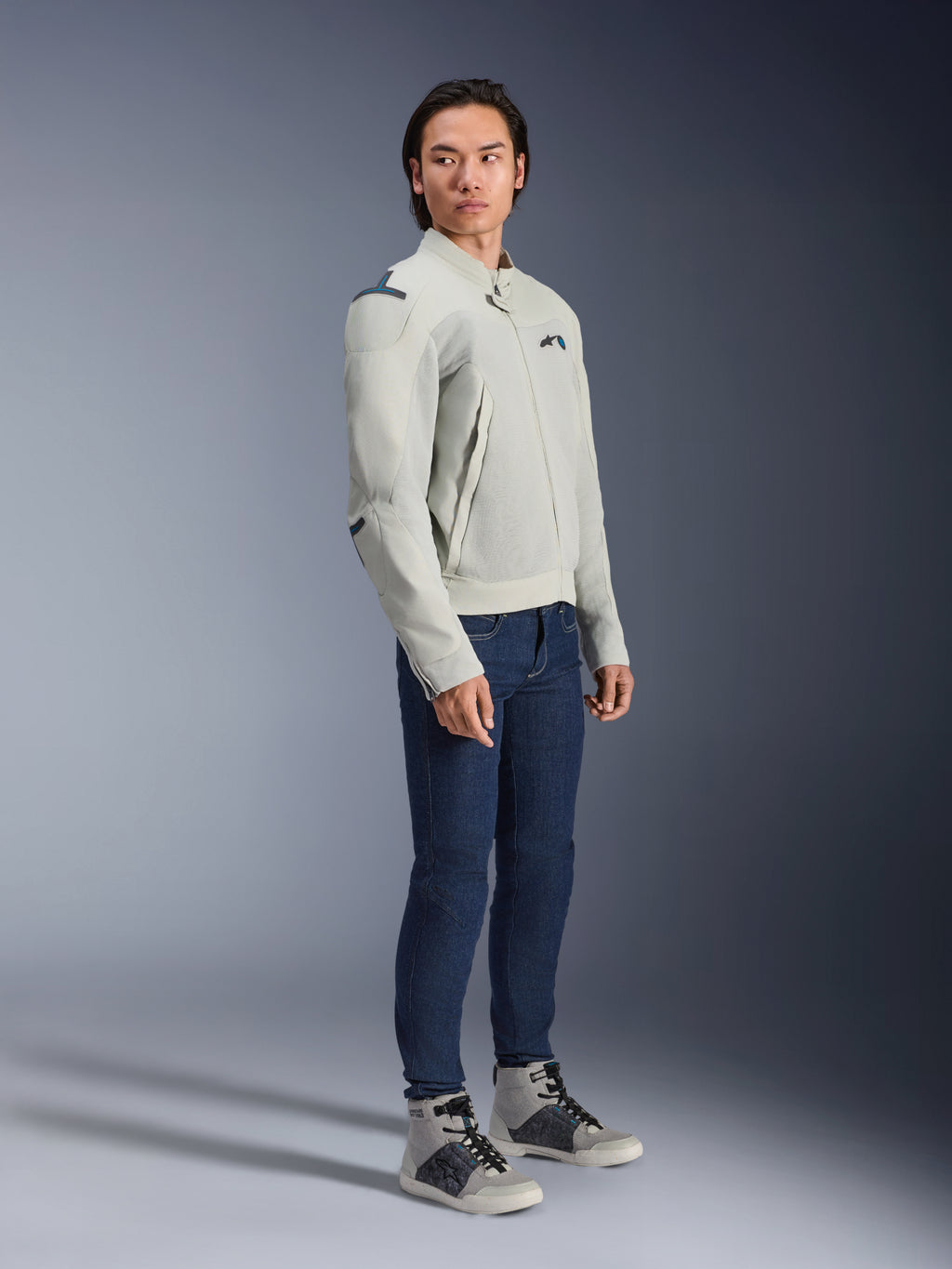 Alpinestars Circal-1 Air-jakke i Metal Gray og Methyl Blue, båret af en model med mørkeblå jeans og grå sneakers, urban sommer-motorcykeljakke med store mesh-ventilationspaneler og et minimalistisk design.