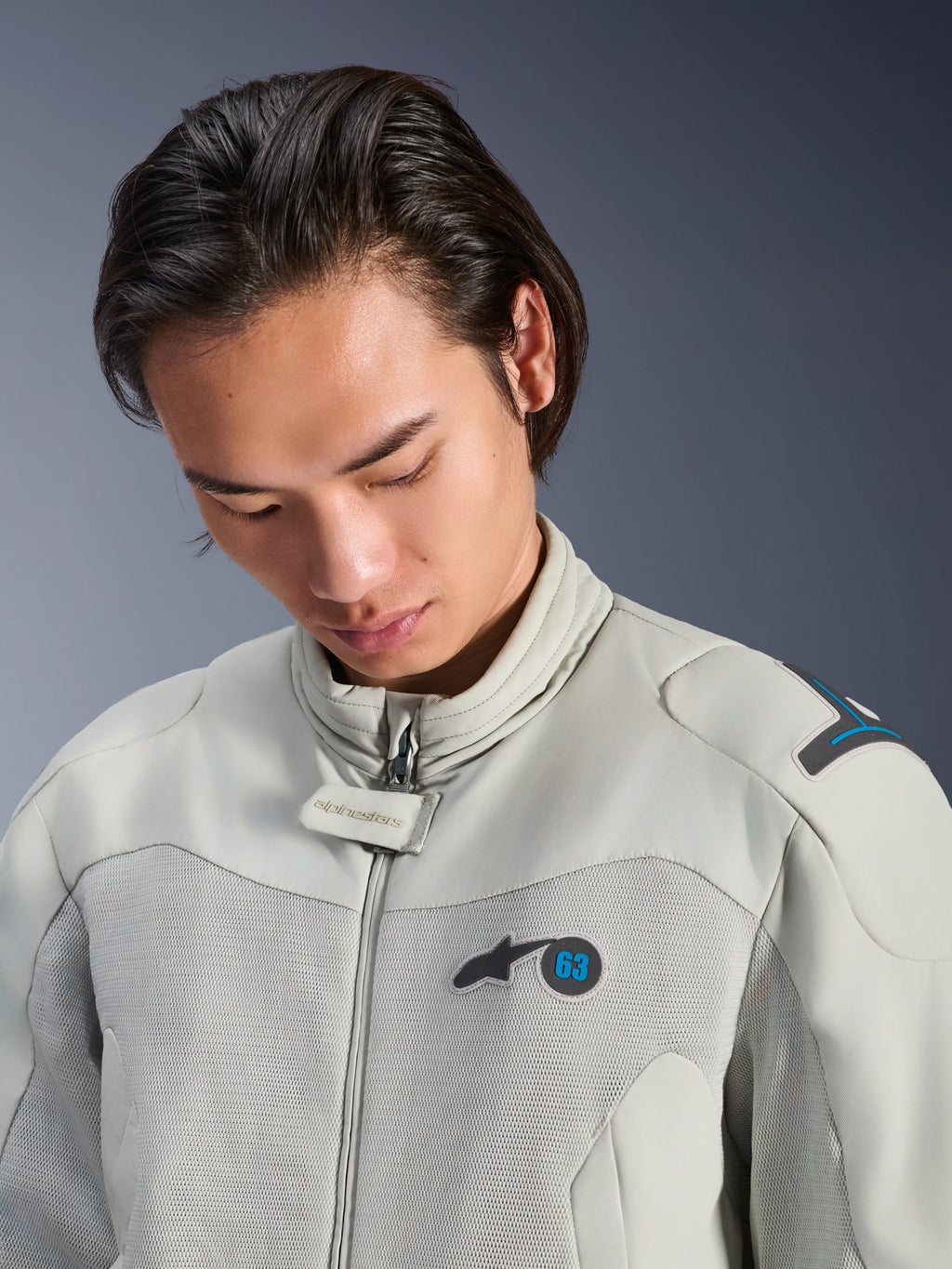 Mandlig model iført Alpinestars Circal-1 Air-jakke i Metal Gray med Methyl Blue-detaljer, nærbillede der fremhæver kraven, mesh-paneler på brystet og minimalistisk logo-branding, bæredygtigt urbant motorcykeludstyr