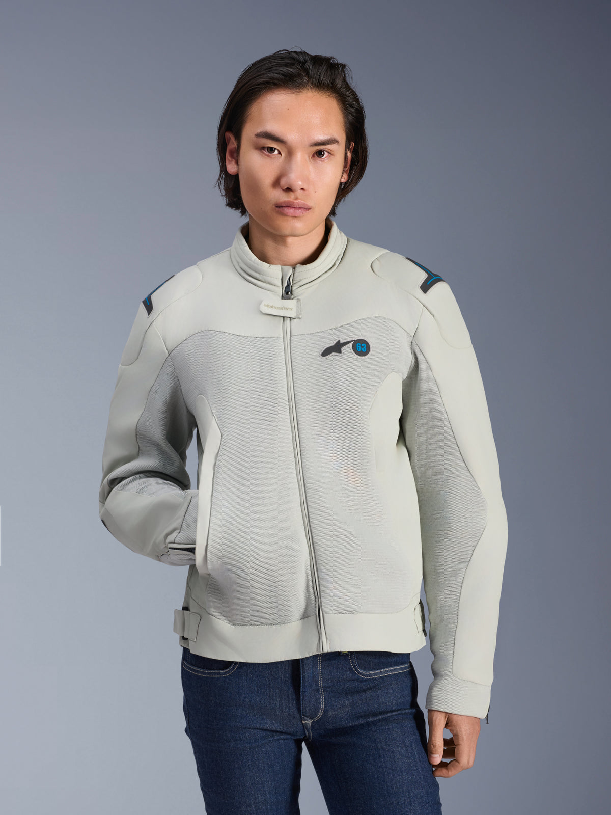 Alpinestars Circal-1 Air-jakke, metalgrå og methylblå, urban motorcykeljakke med mesh-ventilationspaneler, lynlås foran og polstret krave, båret af en model med blå jeans, futuristisk bæredygtigt design til sommerkørsel