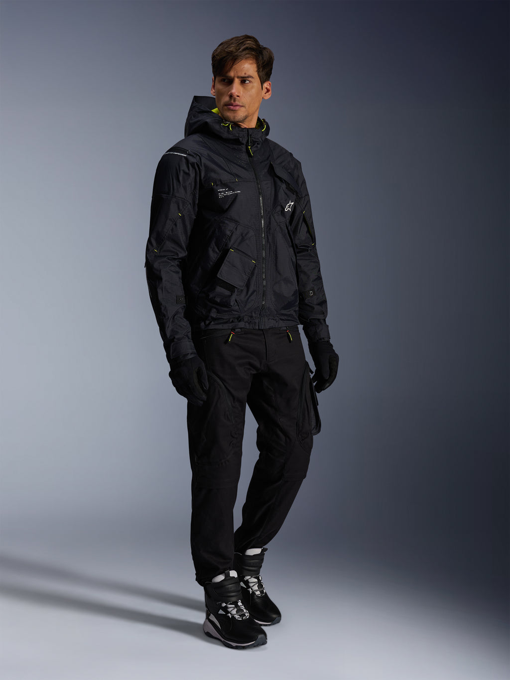 Alpinestars Mogress Air-jakke, urban motorcykeljakke, sort med Lime Punch- og hvide detaljer, båret med sorte kørebukser, handsker og sort-hvide støvler, moderne utility-inspireret design.