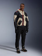 Alpinestars Acteon bukser, sorte motorcykelbukser, her vist med en sort, beige og rød Mogress Air-jakke, sorte kørehandsker og matchende high-top køre-sneakers, moderne urbant motorcykeludstyr til mænd