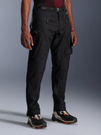 Alpinestars Acteon bukser, sorte motorcykelbukser, vist på en model, med en moderne tilspidset silhuet, cargolommer med lynlås, justerbart taljebælte og tekniske sneakers, urbant køreudstyr